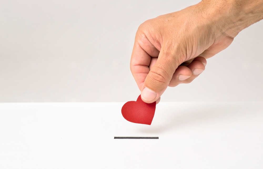 a person putting a red heart symbol on a table