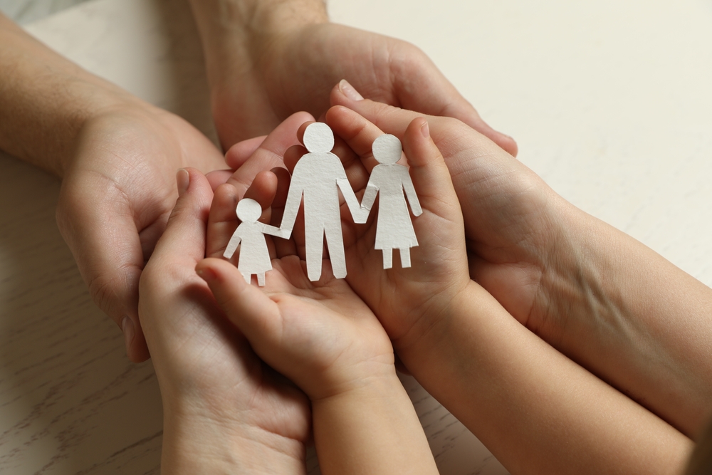 parents and child holding paper cutout of the family